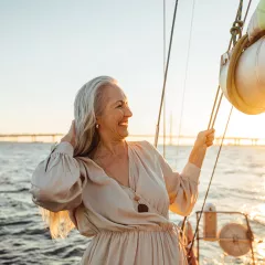 Senior woman adjusting her hair and enjoying sunset on private yacht
