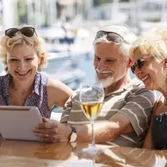 Senior friends smiling and using a digital tablet on a yacht.