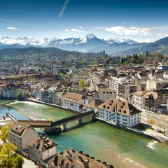 Lucerne ariel city view under warm-looking sunshine and a background of mountain peaks.