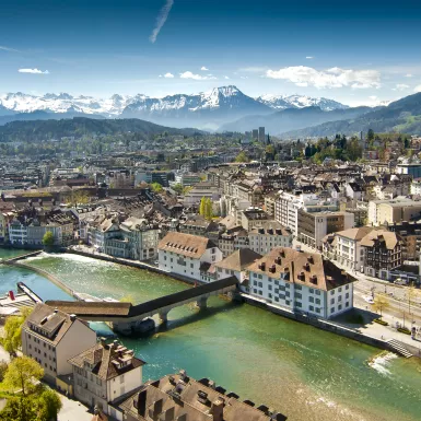 Lucerne ariel city view under warm-looking sunshine and a background of mountain peaks.