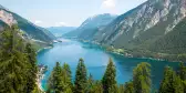 Alpine lake with fir trees and distant mountains in Tyrol, Austria