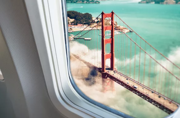 A shot of Golden Gate bridge located in San Francisco, surrounded by mist, taken from a porthole at a high-angle.