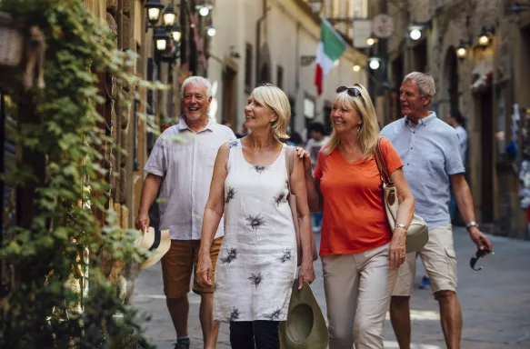 Mature couples looking around old town Italy as evening draws in. Little lights can be seen outside of the buildings.