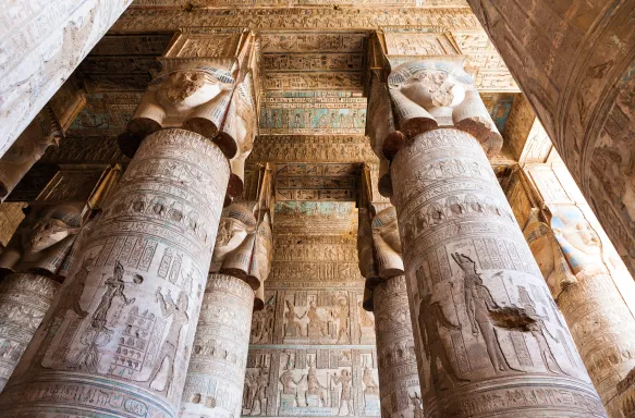 Pillars inside Hypostyle Hall at the Dendera Temple, featuring faded hieroglyphics
