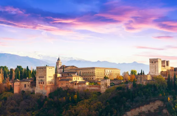 Alhambra palace with Sierra Nevada mountains and a colourful sky in Granada, Spain