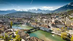 Lucerne ariel city view under warm-looking sunshine and a background of mountain peaks.