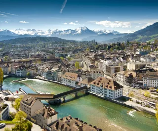Lucerne ariel city view under warm-looking sunshine and a background of mountain peaks.